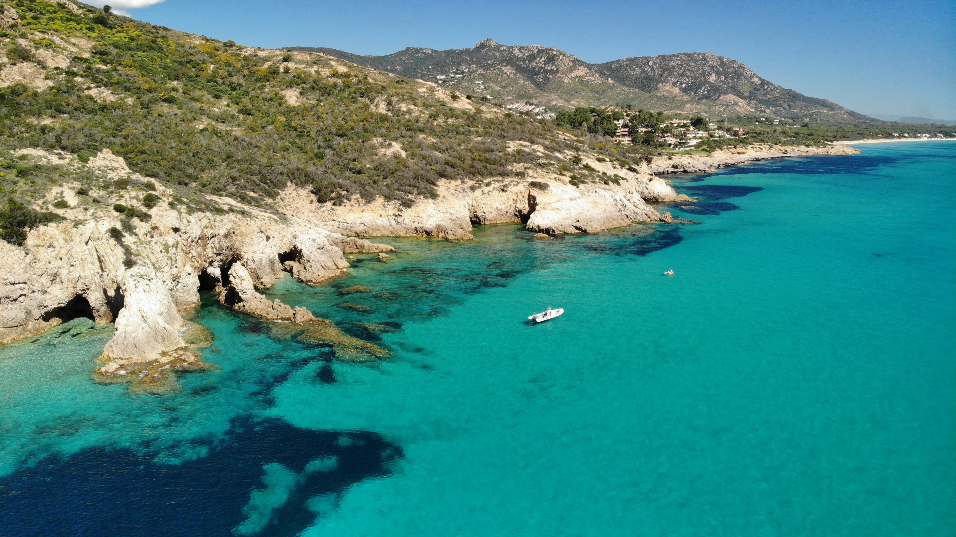 Stella Tours boat anchored beside Sardinian sea cliffs
